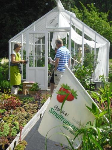 a couple of people standing outside of a greenhouse at Perenner på bakgården in Motala