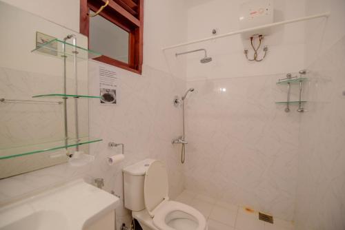 a white bathroom with a toilet and a shower at Muhsin Villa - Galle Fort in Galle