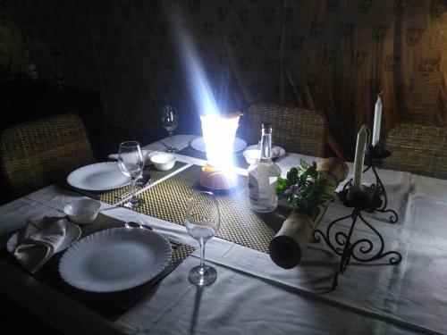 a table with a candle and plates and wine glasses at Samira's Birds & Butterflies Park-Spashram Ganga Beach Retreat in Rishīkesh