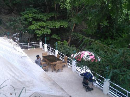 a person sitting at a table next to a fence at Samira's Birds & Butterflies Park-Spashram Ganga Beach Retreat in Rishīkesh