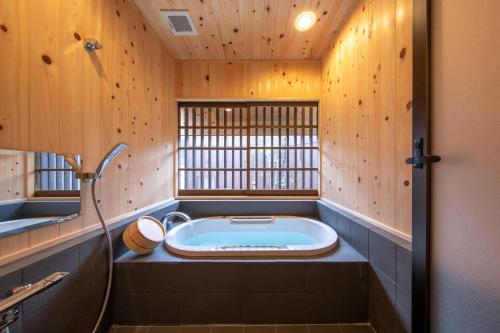 uma casa de banho com banheira num quarto com paredes de madeira em Konpira Machiya USU em Kotohira