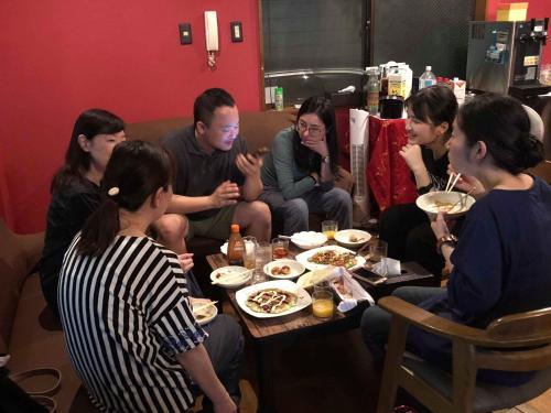 a group of people sitting around a table eating food at HappyCloset&WasamonHostel in Kumamoto