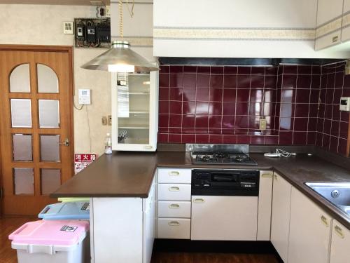 a kitchen with white cabinets and purple tiles at Guesthouse LARGO in Odawara