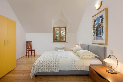 een witte slaapkamer met een bed en een houten vloer bij Villa Dubrava Tranquil Retreat Nestled in an Olive Grove for Serene Escapes in Pučišća