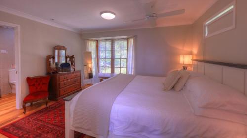 Un dormitorio con una gran cama blanca y una alfombra roja en The Avenue at Montville Cottage, en Montville