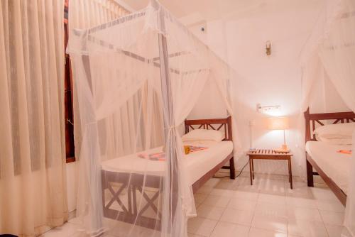 a bedroom with two beds with mosquito nets at Muhsin Villa - Galle Fort in Galle
