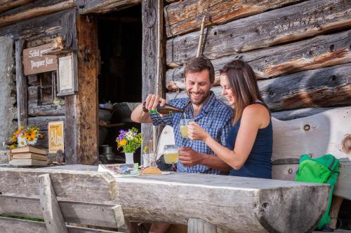 a man and a woman sitting at a table with a drink at Pension Jaga Hias in Kaprun