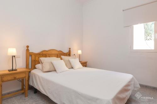 a bedroom with a bed with white sheets and a window at Sa Marina in Alcudia