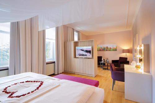 ein Hotelzimmer mit einem Bett und einem Wohnzimmer in der Unterkunft Hotel Haus Delecke in Möhnesee