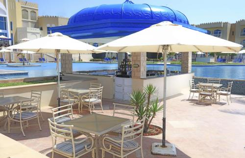 a patio with tables and umbrellas and a pool at Wyndham Garden Salalah Mirbat in Salalah