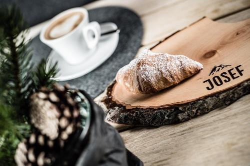 a piece of bread and a cup of coffee on a table at Josef Mountain Resort in Avelengo