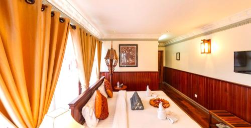 a room with a bed and a tv and curtains at Okay Boutique Hotel in Phnom Penh