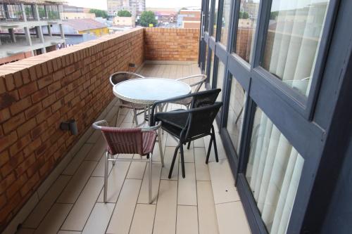 a balcony with a table and chairs and a window at Alcazaba Hotel in Johannesburg