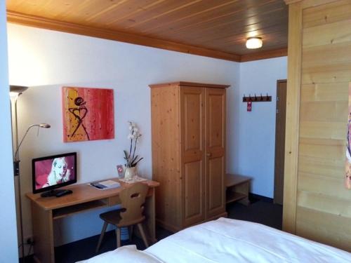 a bedroom with a bed and a desk with a computer at Sonnegg Hotel in Zweisimmen