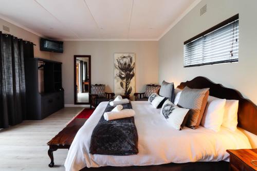 um quarto com uma cama grande e almofadas em Arbour1 Guesthouse em George