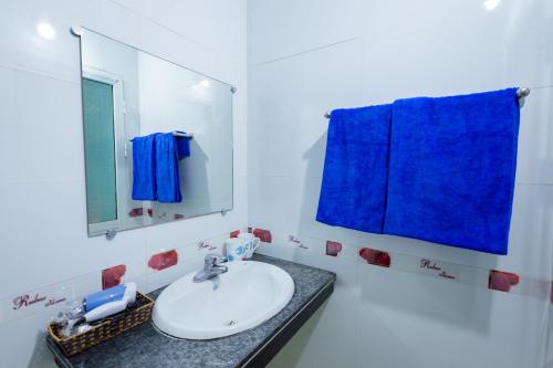 a bathroom with a sink and a mirror and blue towels at Phoenix Flower Hotel in Cat Ba