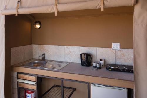 a kitchen with a sink and a stove at Desert Camp in Sesriem