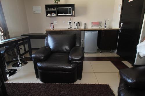 a black leather chair in a room with a kitchen at Alcazaba Hotel in Johannesburg