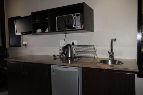 a kitchen counter with a sink and a microwave at Alcazaba Hotel in Johannesburg