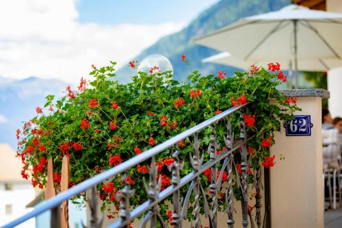 a bunch of red flowers on a railing at Hotel Helvetia in Müstair