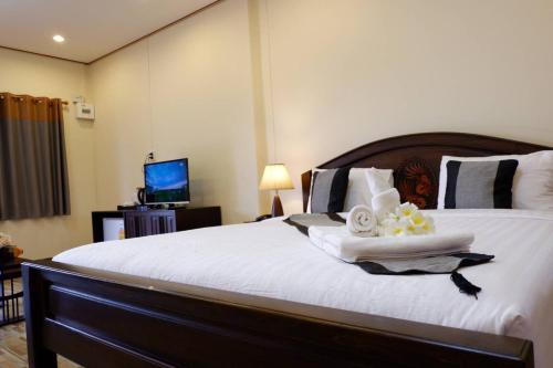 a bedroom with a large white bed with towels on it at NanBaanKhun Hotel in Nan