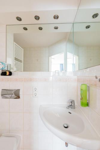 a white bathroom with a sink and a mirror at Hotel Restaurant Fallerhof in Bad Krozingen
