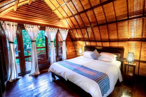 a bedroom with a bed in a room with windows at Manta Dive Gili Air Resort in Gili Air