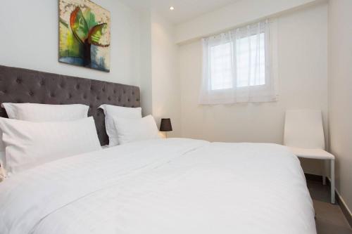 - un lit blanc avec des oreillers blancs et une fenêtre dans l'établissement MARTINEZ AREA: NEW 2BEDS/2BATHS, à Cannes