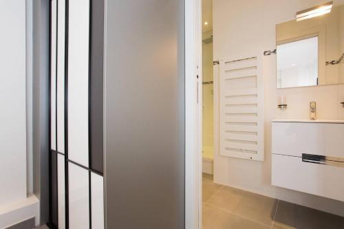 La salle de bains est pourvue de murs blancs, d'un lavabo et d'un miroir. dans l'établissement MARTINEZ AREA: NEW 2BEDS/2BATHS, à Cannes