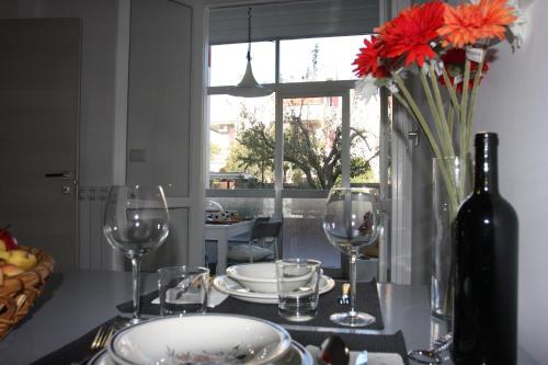 a table with wine glasses and a vase with red flowers at Villa della Tartaruga in Casal Palocco