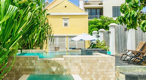 uma piscina com um guarda-sol e uma casa em Pietermaai Boutique Hotel em Willemstad
