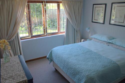 a bedroom with a bed and two windows at Menlo At C in Plettenberg Bay