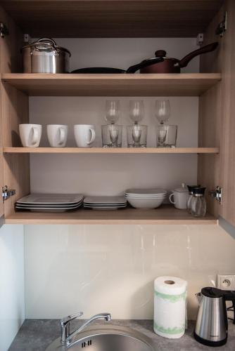 a kitchen shelf with dishes and wine glasses on it at Metropolis Apartamenty Centrum in Kalisz