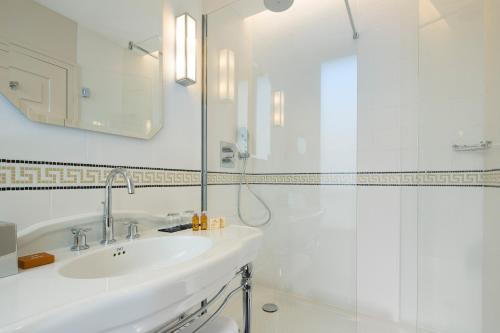 a white bathroom with a sink and a shower at Le Tsuba Hotel in Paris