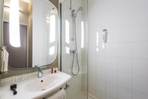 a bathroom with a sink and a shower with a mirror at ibis Bordeaux Centre - Gare Saint-Jean in Bordeaux