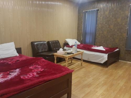Zimmer mit 2 Betten, einem Stuhl und einem Tisch in der Unterkunft Khunjerab Hotel Sost in Gircha
