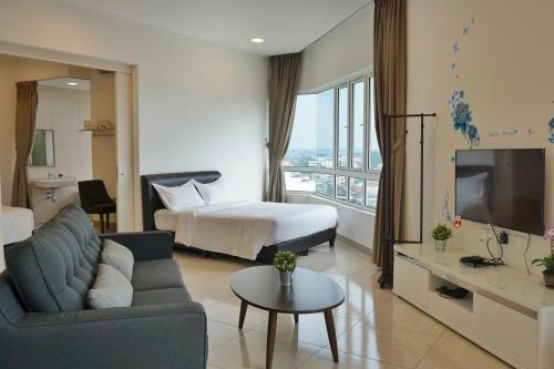 a hotel room with a bed and a couch and a tv at PM Octagon Ipoh Suites & Apartment 3 in Ipoh