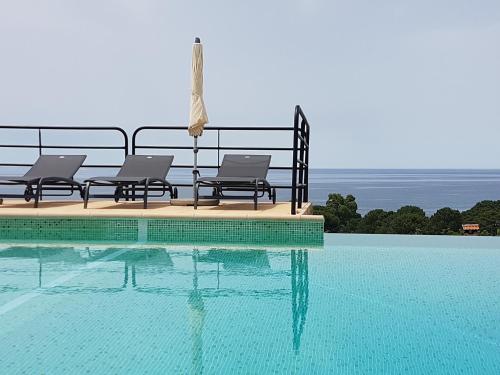 uma piscina com três cadeiras sentadas junto à água em Résidence Costa d'Oru em Saint-Florent