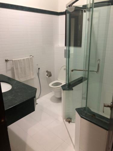 a bathroom with a toilet and a glass shower at Sunset Suites in Karachi