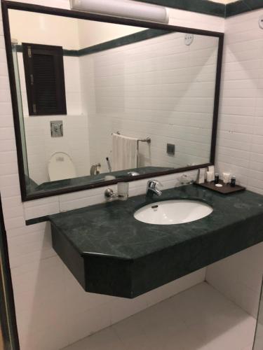 a bathroom with a sink and a large mirror at Sunset Suites in Karachi