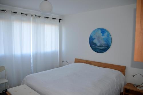 a bedroom with a white bed and a blue clock on the wall at Haus Calmsailing in Börgerende-Rethwisch