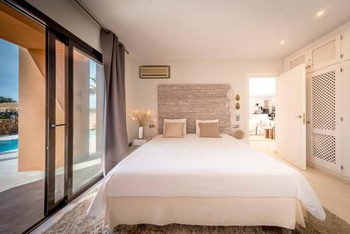 a bedroom with a white bed and a large window at La Villa in Cala Vadella