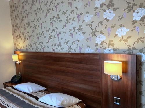 a bedroom with a wooden headboard with flowers on the wall at Ely House Hotel in Wolverhampton