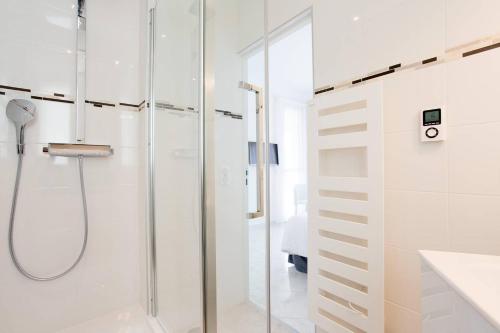 La salle de bains blanche est pourvue d'une douche et d'une porte en verre. dans l'établissement MARIOTT AREA: SUNNY 2 BEDS /2 BATHS, à Cannes