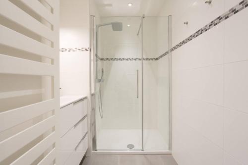 La salle de bains est pourvue d'une douche en verre et de murs blancs. dans l'établissement Palais Miramar: 1 bed side sea view, à Cannes