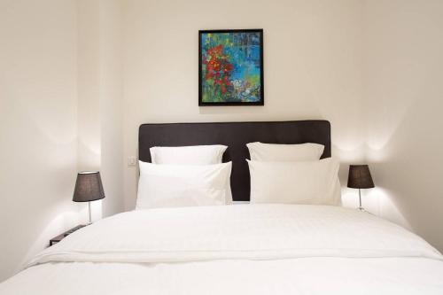 - un lit blanc avec des oreillers blancs et un tableau dans l'établissement Palais Miramar: 1 bed side sea view, à Cannes