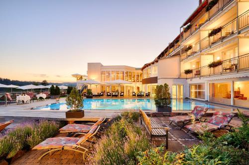 a hotel with a swimming pool with lounge chairs next to it at Hotel Kronelamm im Schwarzwald in Bad Teinach-Zavelstein