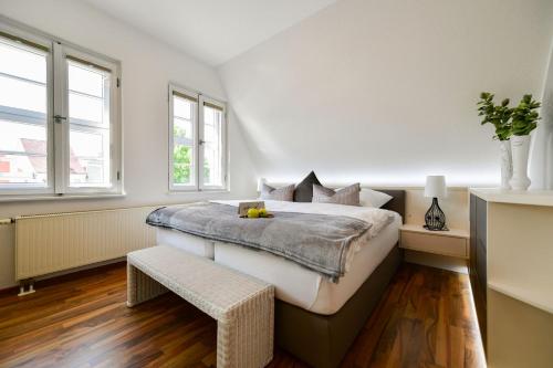 ein weißes Schlafzimmer mit einem großen Bett und zwei Fenstern in der Unterkunft Altstadt Apartment Deluxe in Cottbus