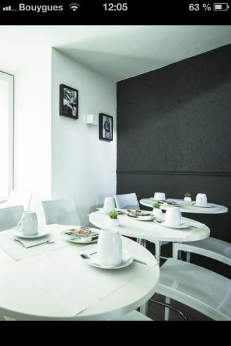 een eetkamer met witte tafels en witte stoelen bij Hotel Schtak in Cannes