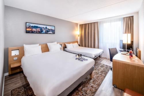 een hotelkamer met 2 bedden en een bureau bij Novotel Eindhoven in Eindhoven